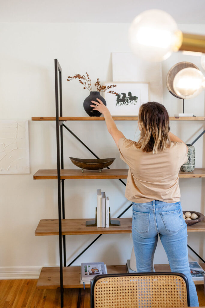 Stock image of a woman styling a bookcase to illustrate a property preparation service.