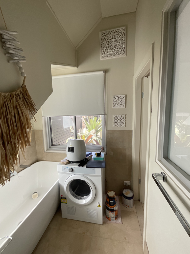 Image of the ground floor cupboard under the back stairs which has a bathtub and dryer in it. This space will be converted to a pantry.