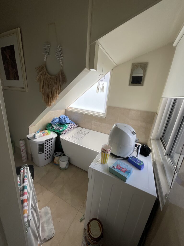 Before photo of the cupboard with a bathtub, dryer and lots of stored items