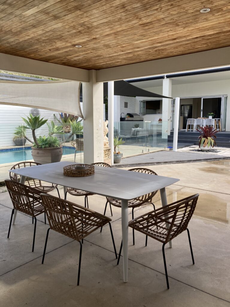 View of the outdoor area from the second dining space. The pool, outdoor kitchen and dining space under the covered deck are shown.