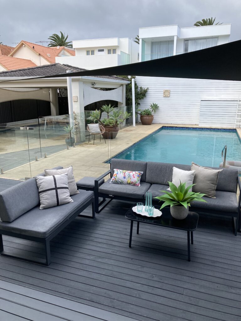 Outdoor sitting area with the pool behind it and an additional outdoor living space under the carport in the background