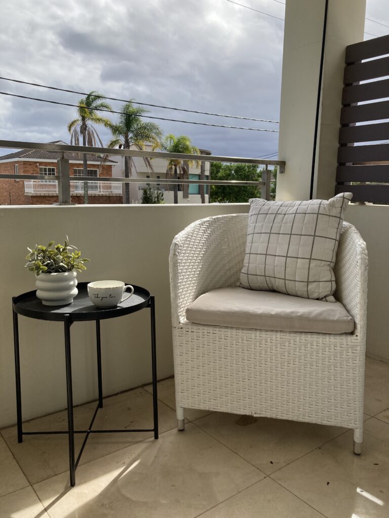 Outdoor armchair, side table with plant and mug on the front balcony