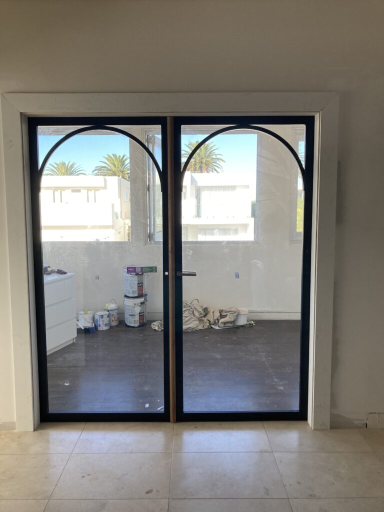 Photo of the new doors from Corinthian installed in the space. They were primed black and we planned to paint them white.