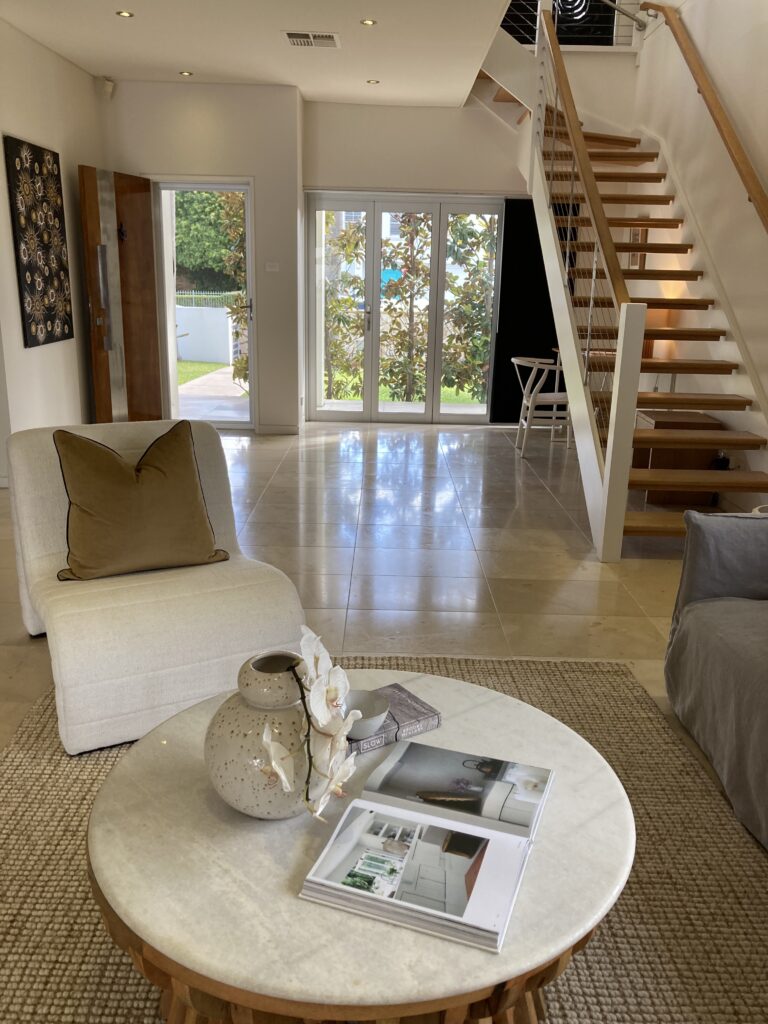 View of living room through the open front door. Stairs and study nook also shown