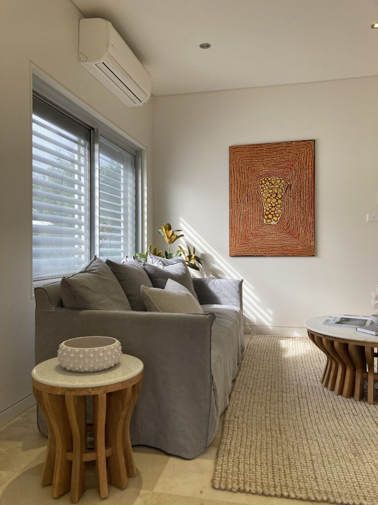 Living room with couch, side table, coffee table and Aboriginal artwork