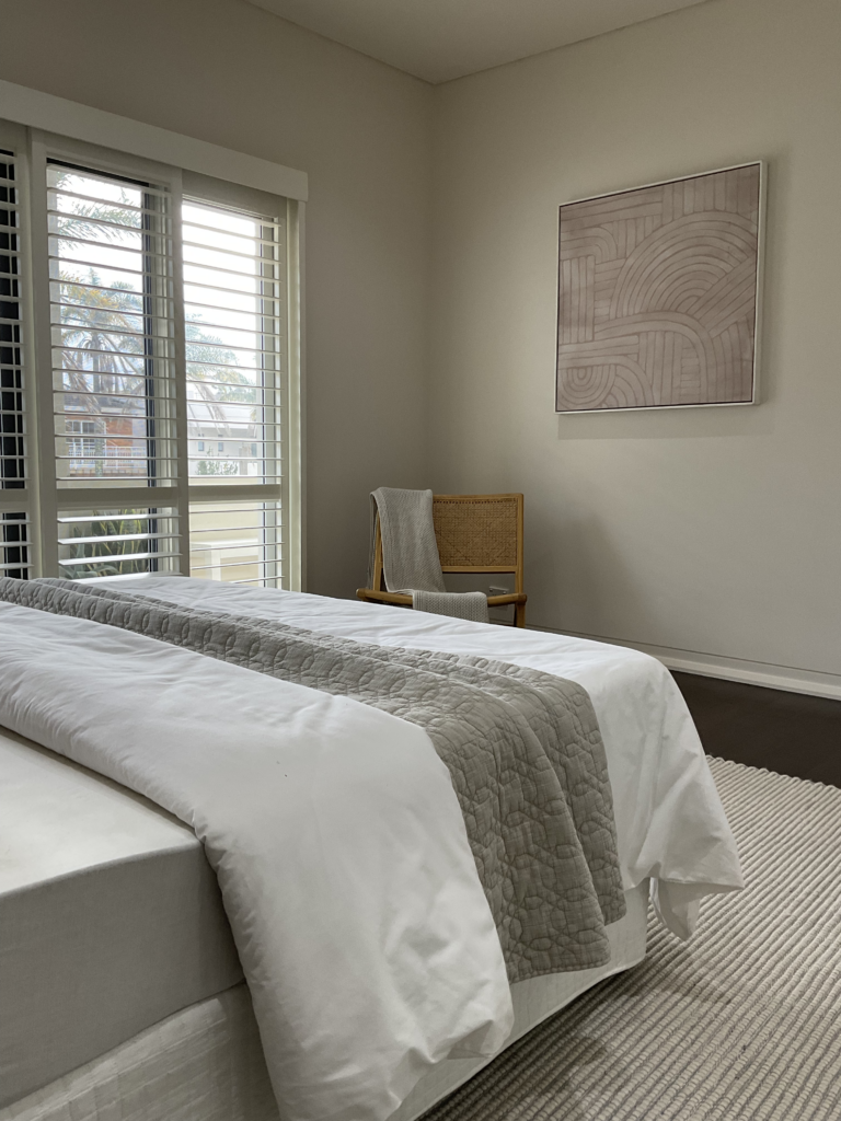 Bed, artwork, armchair and plantation shutters in the main bedroom