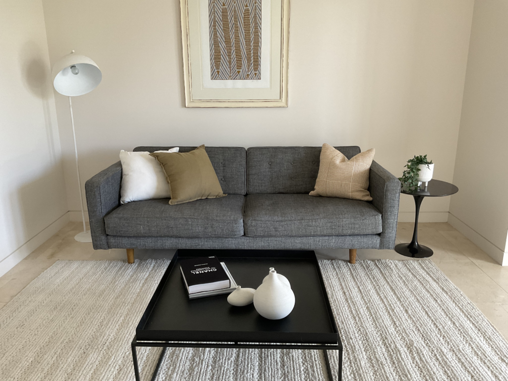 Family room with couch, floor lamp, side table with plant, coffee table and artwork on the wall