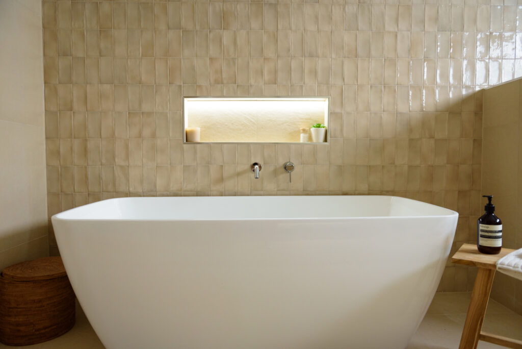 Image of the bathtub, feature tile wall and niche with the light on