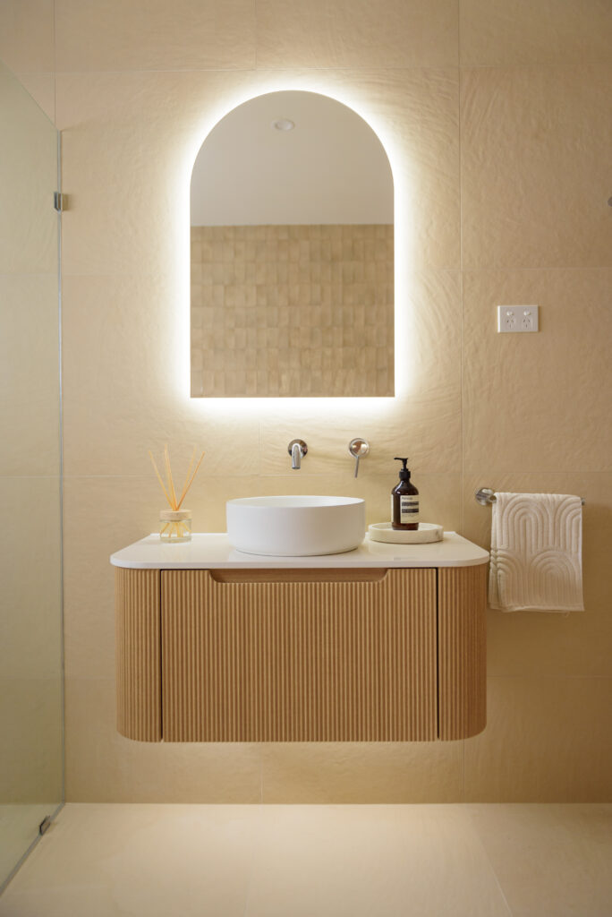 Photo of the renovated bathroom of 88 Clareville Avenue with a fluted vanity, white above counter basin, and LED mirror