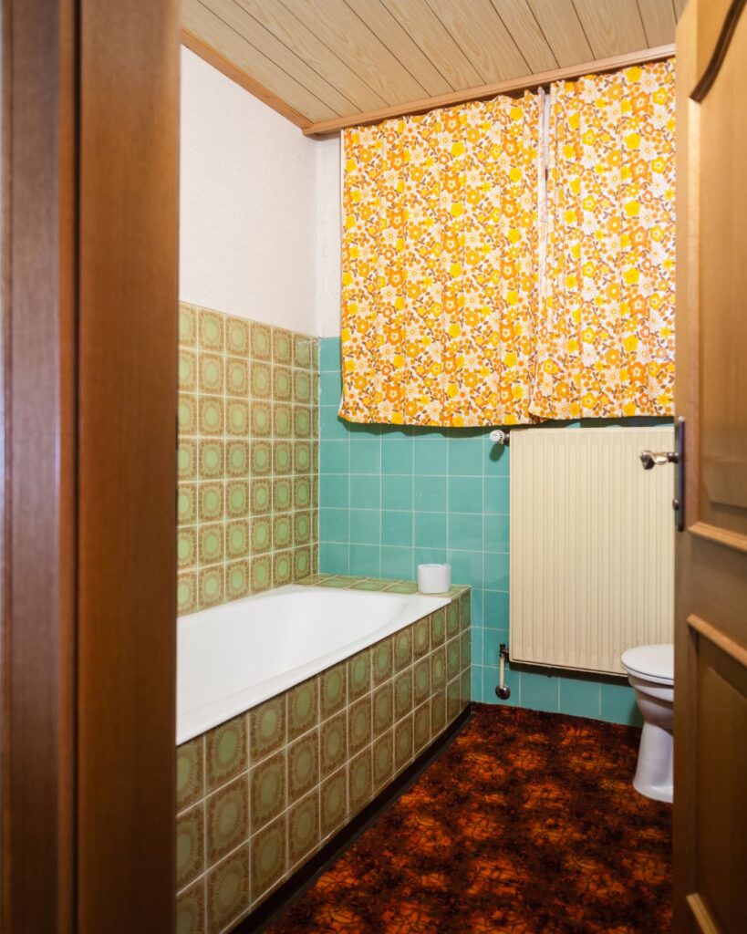 Stock image of an outdated bathroom including old tile and carpeted flooring