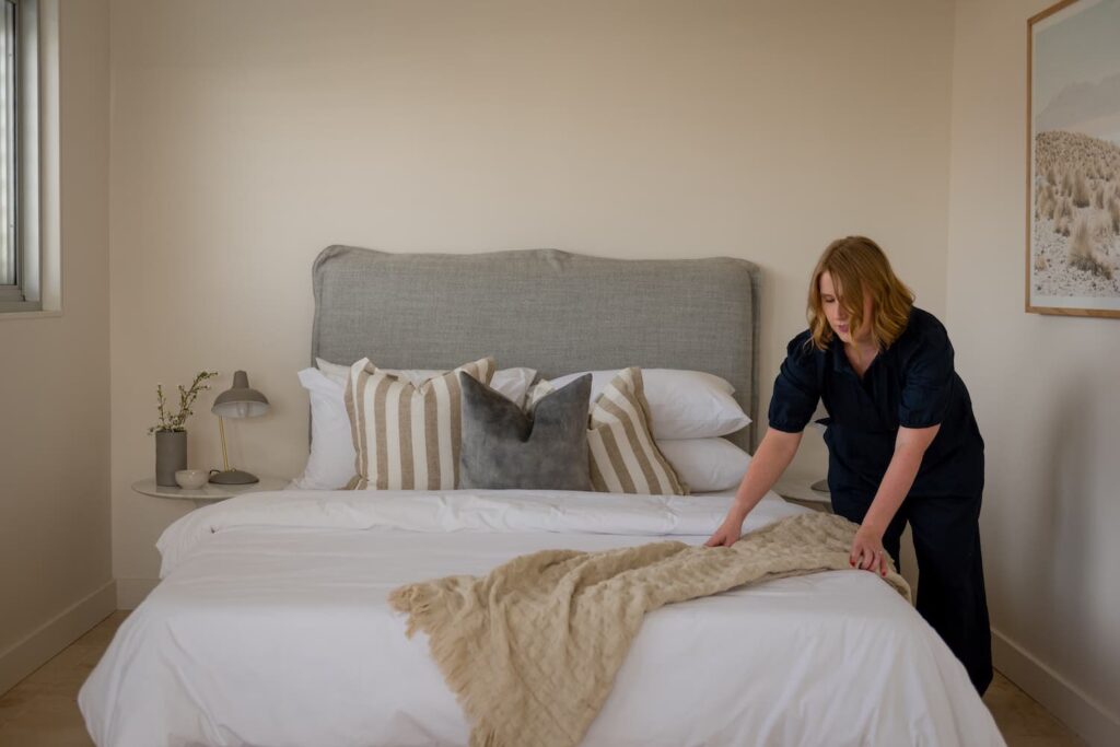 Kristen adjusting the throw rug on the bed at the Sandringham pre-sale renovation