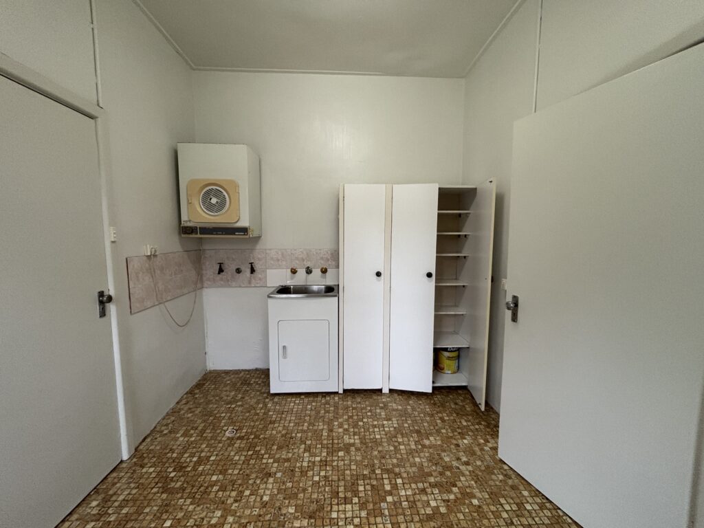 Before photo of the Sydney semi laundry renovation with old cabinetry, and dated brown tiles.