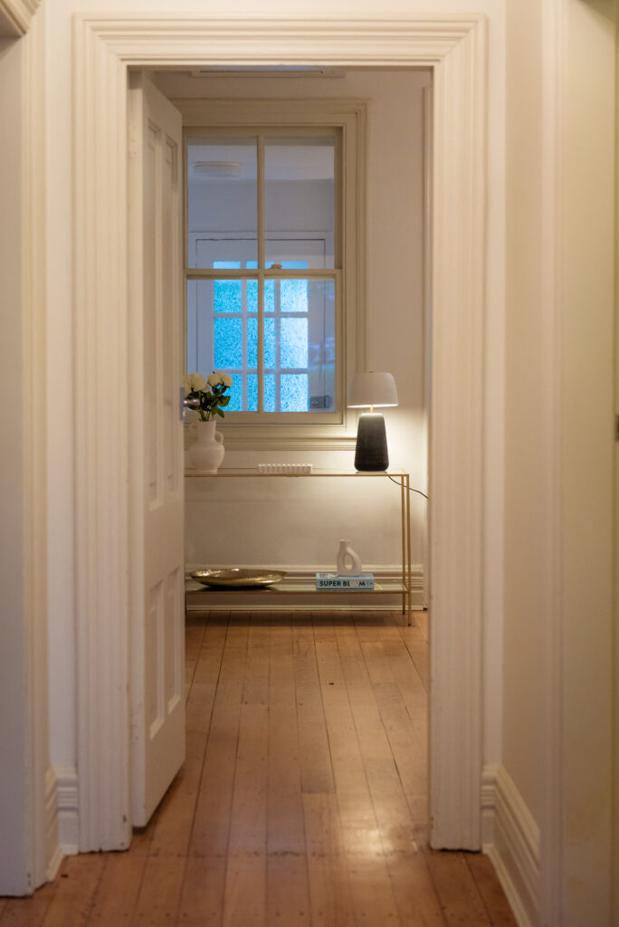 After image of the hallway looking into the living room with refinished floors and styling