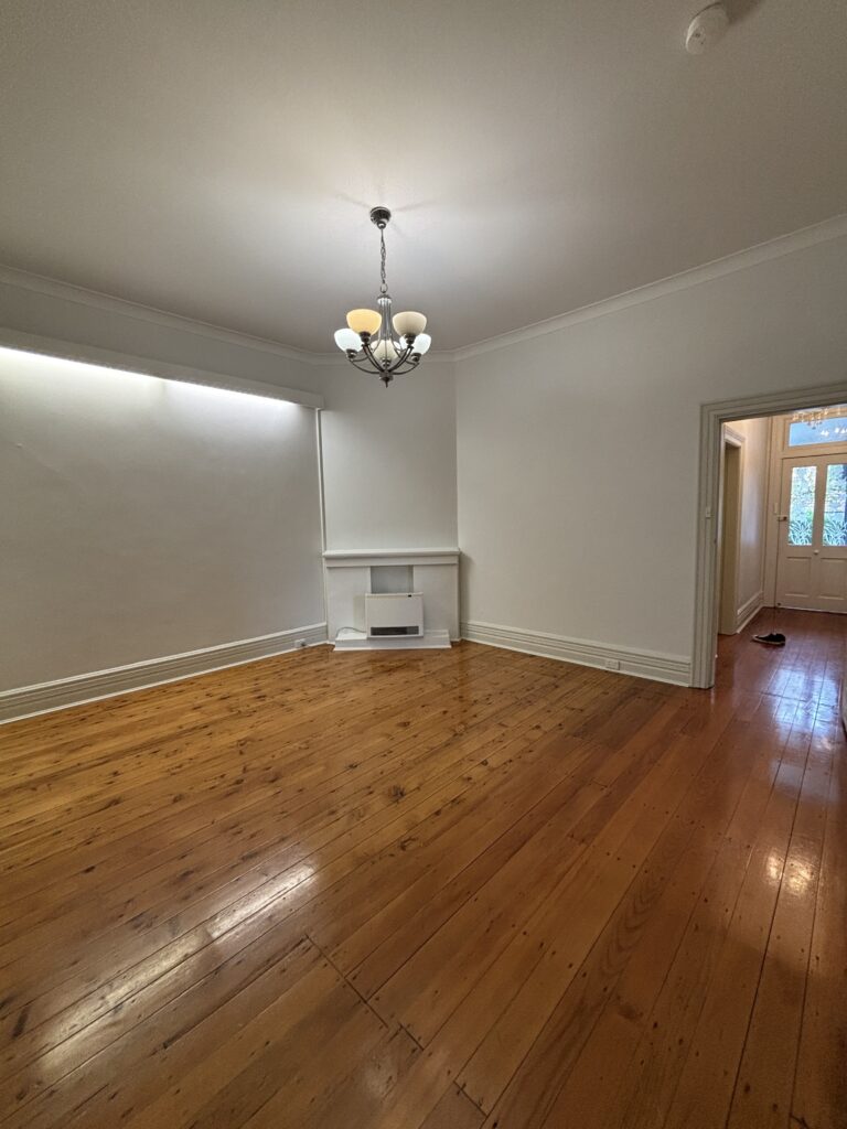 Before image of the living room with fluro lighting and orange floors