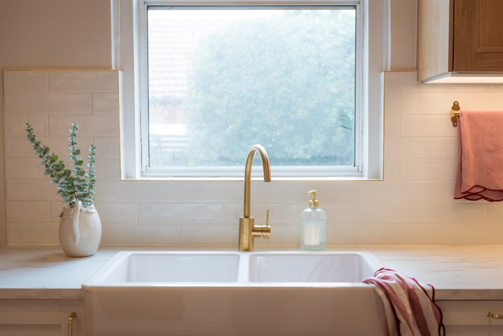 After image of the kitchen sink, a double white farmhouse sink and gold tapware